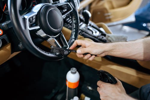 detailer de interior limpiando el volante de un coche